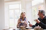 Smiling, happy mature couple eating breakfast, drinking coffee