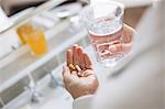 Woman taking vitamins and glass of water