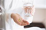 Woman taking vitamins with glass of water