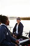 Female rowers talking, carrying scull