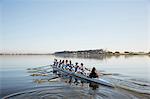 Female rowing team rowing scull on tranquil lake
