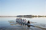 Female rowing team rowing scull on tranquil lake