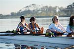 Female rowing team rowing scull on sunny lake