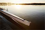 Scull at dock on tranquil sunrise lake