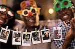 Portrait playful family in Christmas costume goggles showing instant photos