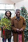 Portrait smiling grandfather and grandson arriving with Christmas gift and mistletoe