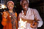 Portrait happy senior father and daughter celebrating with sparklers