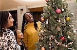 Mother and daughters looking up at Christmas tree