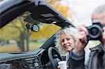 Senior couple using digital camera in convertible