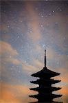 Silhouette of tall wooden pagoda of Buddhist temple against evening sky.