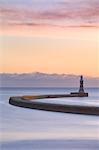 The colours of a winter sunrise over the curving pier and lighthouse at Roker, Sunderland, on the North East Coast, England, United Kingdom, Europe