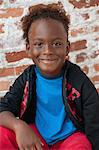 Portrait of young boy sitting outdoors, smiling