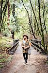 Young woman near forest footbridge looking up