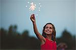 Girl with arm raised holding sparkler