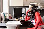 A black office superhero businesswoman takes a call in her office from a client.
