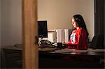 An Hispanic businesswoman office super hero at her office computer