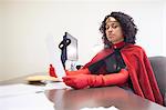 Portrait of a black businesswoman office super hero sitting at her office computer.