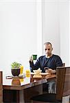 Hispanic man checking his phone at the dinning room table in a new home.