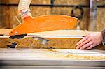 Close up of person cutting piece of recycled wood with a circular saw.