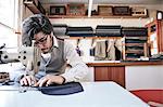 Man sewing a garment using an industrial sewing machine, at a family tailoring business workshop.