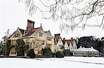 Historic 17th century manor house with tall chimneys, a hotel with snow covered grounds in winter.