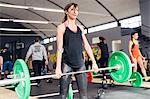 Young woman weightlifting  with barbell in gym