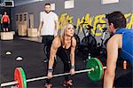 Man and woman in gym with barbells weightlifting