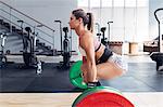 Side view of woman weightlifting barbell in gym