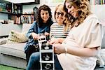 Pregnant woman and friends on sofa looking at ultrasound pictures