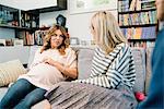 Pregnant woman and friends chatting on sofa