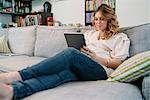 Pregnant woman on sofa looking at digital tablet