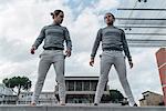 Young adult male twins training, standing on wall, low angle view