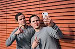 Young adult male twins taking a training break, taking selfie
