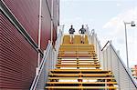 Young adult male twins running together, running down city stairway