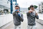 Identical male adult twin boxers training outdoors, fighting stance portrait