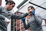 Identical male adult twin boxers training outdoors, practicing punches