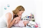 Mother playing with baby on changing table