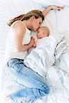 Mother kissing sleeping baby in bed