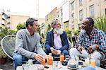 Friends chatting over drinks outdoors, London, UK