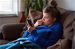 Young woman on sofa looking at smartphone