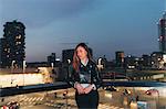 Portrait of mid adult woman standing on balcony at dusk, pensive expression