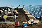 Engineers connecting solar panels on new solar farm, situated on former waste dump