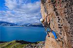 Young male climber climbing sandstone rockface, Narsaq, Vestgronland, South Greenland