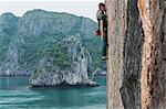 Man rock climbing on limestone rock, Ha Long Bay, Vietnam