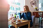 Two female friends sitting together in cafe, drinking coffee