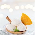 White ice cream in plate with waffle on bright rustic wooden background.
