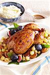 Honey roasted chicken with figs and onions served on a platter with side dishes of mashed potatoes and gravy