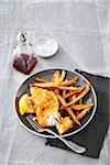 Fish and chips with malt vinegar on a grey backround