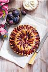 Plum cake with fresh plums and whipped cream and serving knife