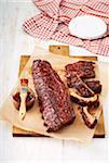 BBQ ribs with barbeque sauce and brush on a cutting board with parchment paper